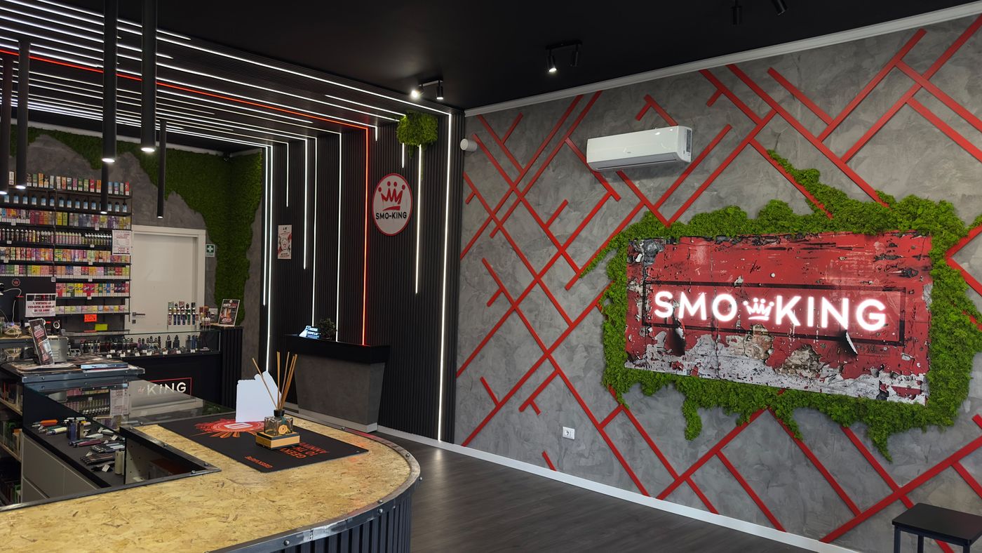 Parete con logo Smo-King e muschio decorativo nel negozio di Cassino, con scaffali di liquidi ai lati
