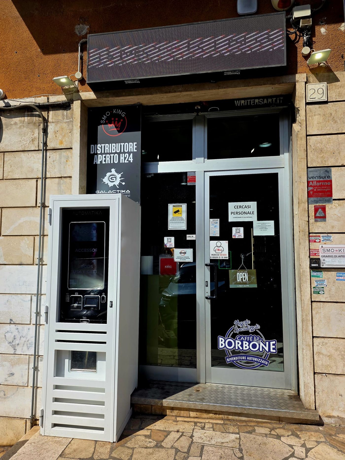 Ingresso del negozio Smo-King di sigarette elettroniche in Via dei Gelsi 29/A a Roma, con il distributore automatico accanto alla porta