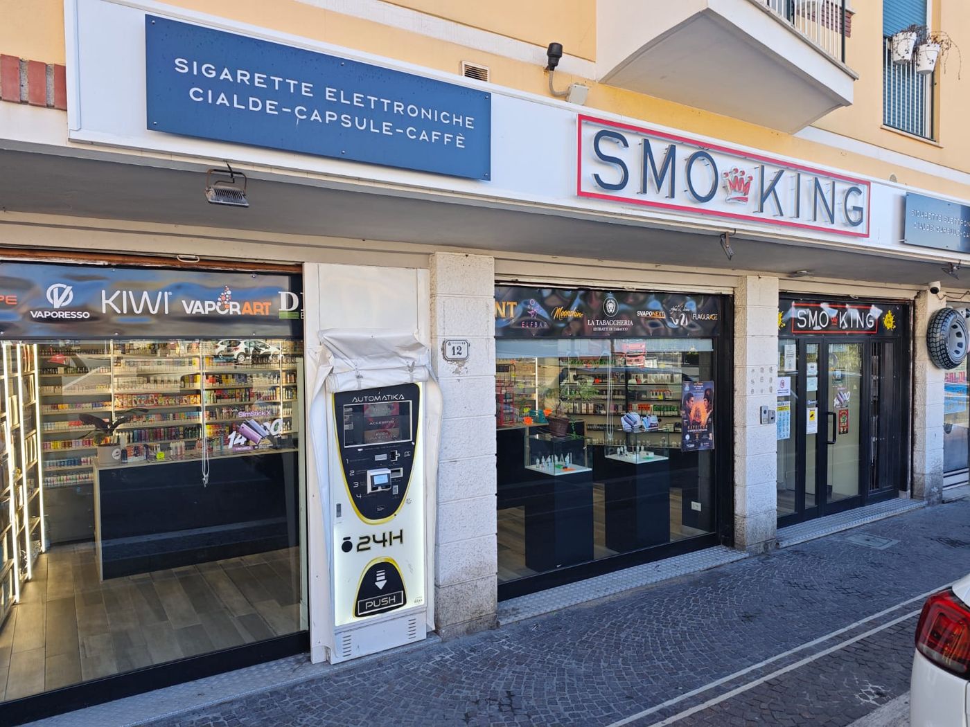 Ingresso del negozio Smo-King di Nettuno in Piazza San Francesco 12, con insegna Smo-King Sigarette Elettroniche Cialde Capsule Caffè e distributore automatico 24h
