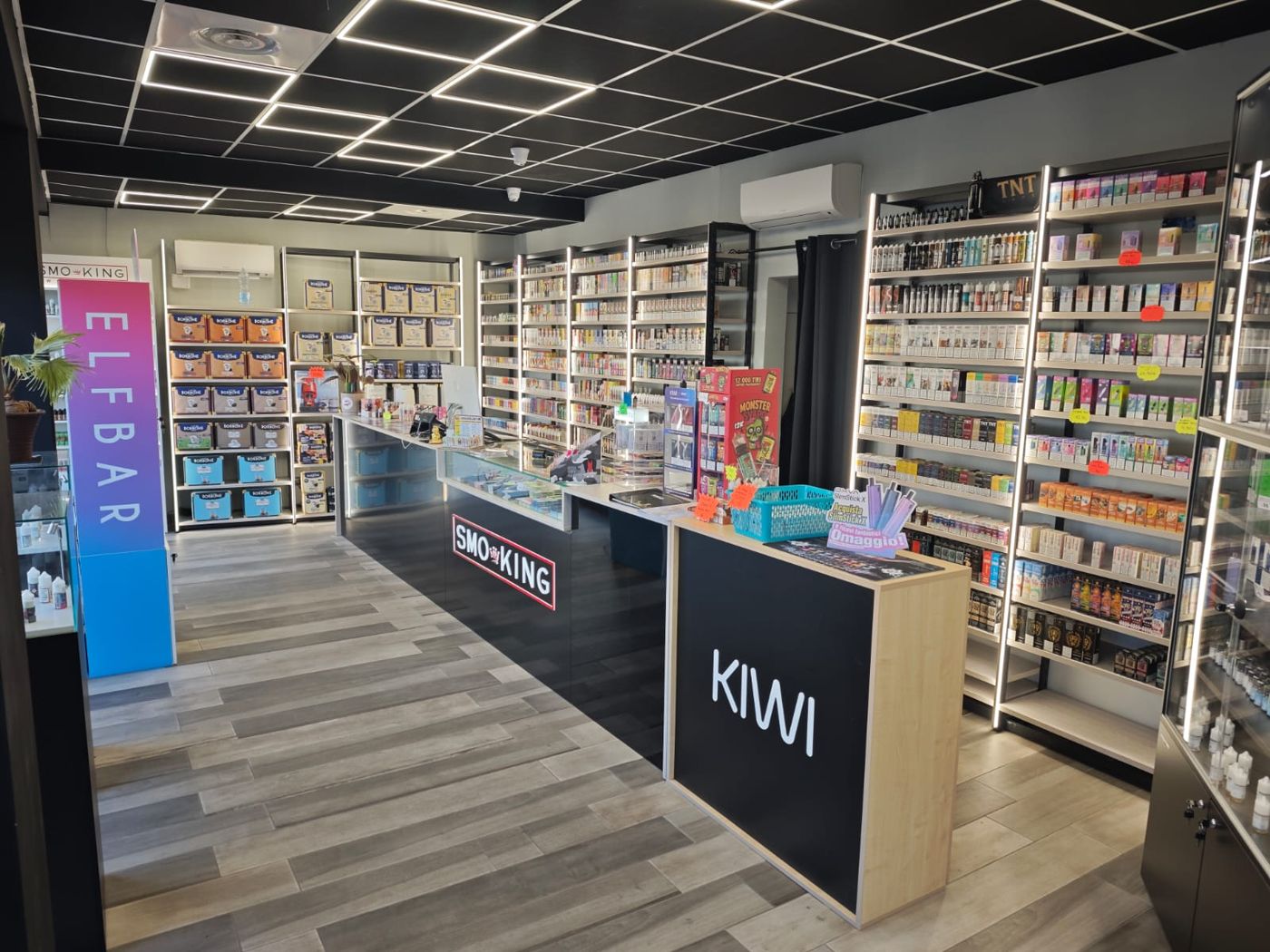 Interno del negozio Smo-King di Nettuno con bancone, espositore KIWI e pareti di liquidi e usa e getta