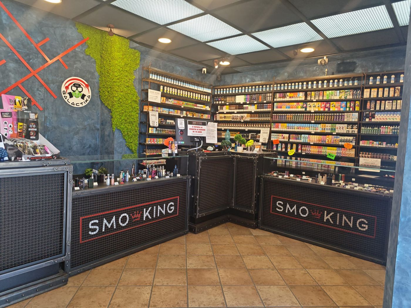 Interno del negozio Smo-King di Badino con banconi Smo-King, parete di muschio e scaffali di liquidi