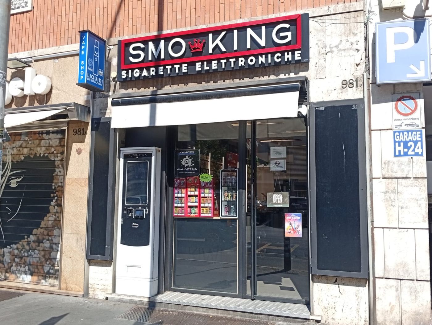 Ingresso del negozio Smo-King di Via Tuscolana 981b a Roma, con insegna Smo-King Sigarette Elettroniche e distributore automatico accanto alla porta