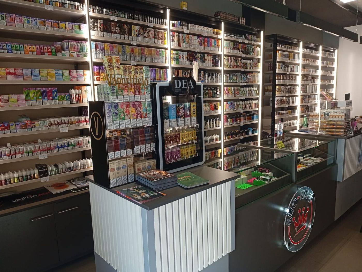 Interno del negozio Smo-King di Via Tuscolana con bancone, espositore DEA e pareti di liquidi e aromi