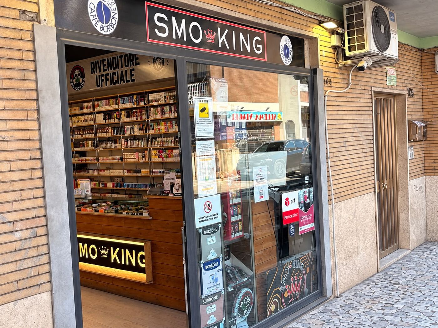 Ingresso del negozio Smo-King di Via di Casalotti 103/A a Roma, con insegna Smo-King Sigarette Elettroniche e targa rivenditore ufficiale